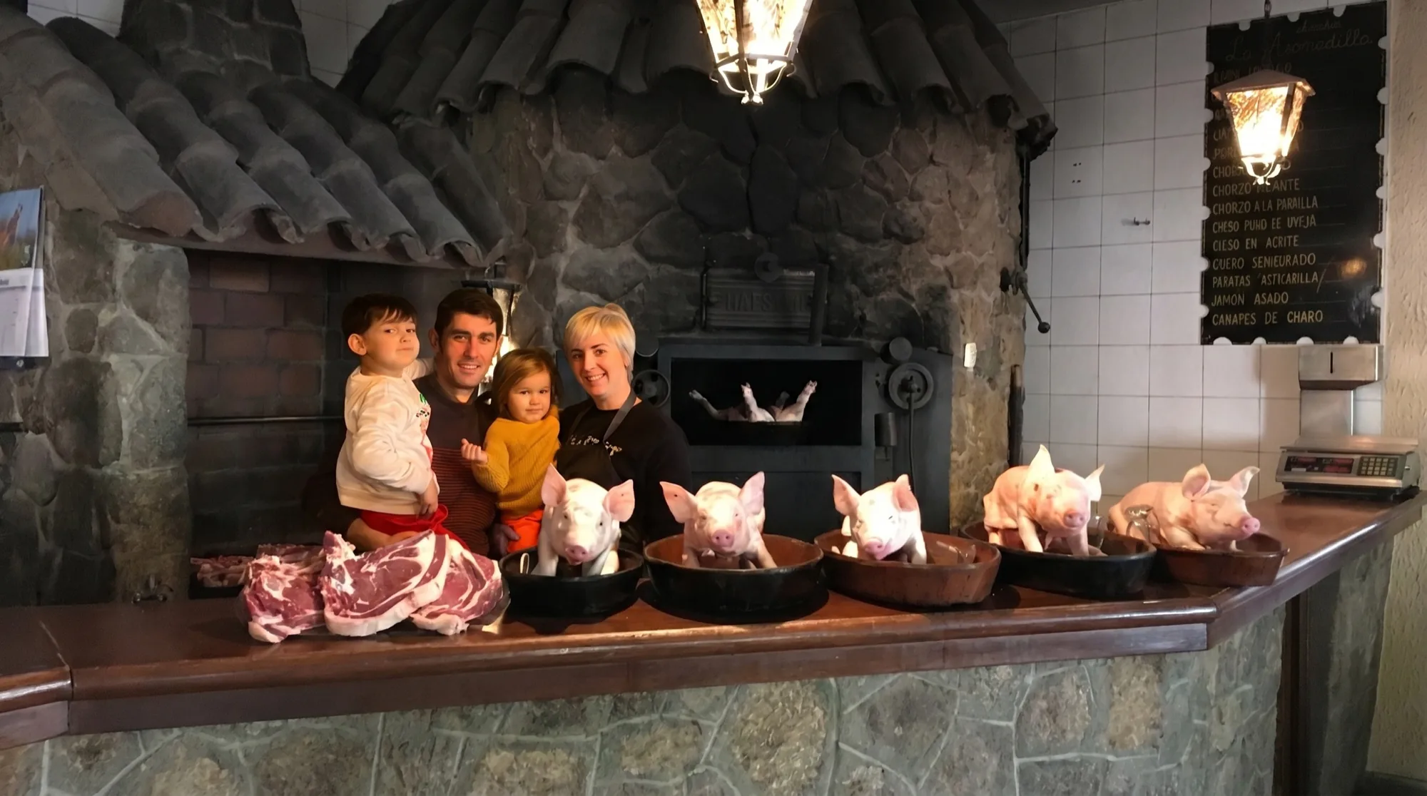 Marta y su familia, segunda generación del Asador Asomadilla, ante el horno de leña con los cochinillos